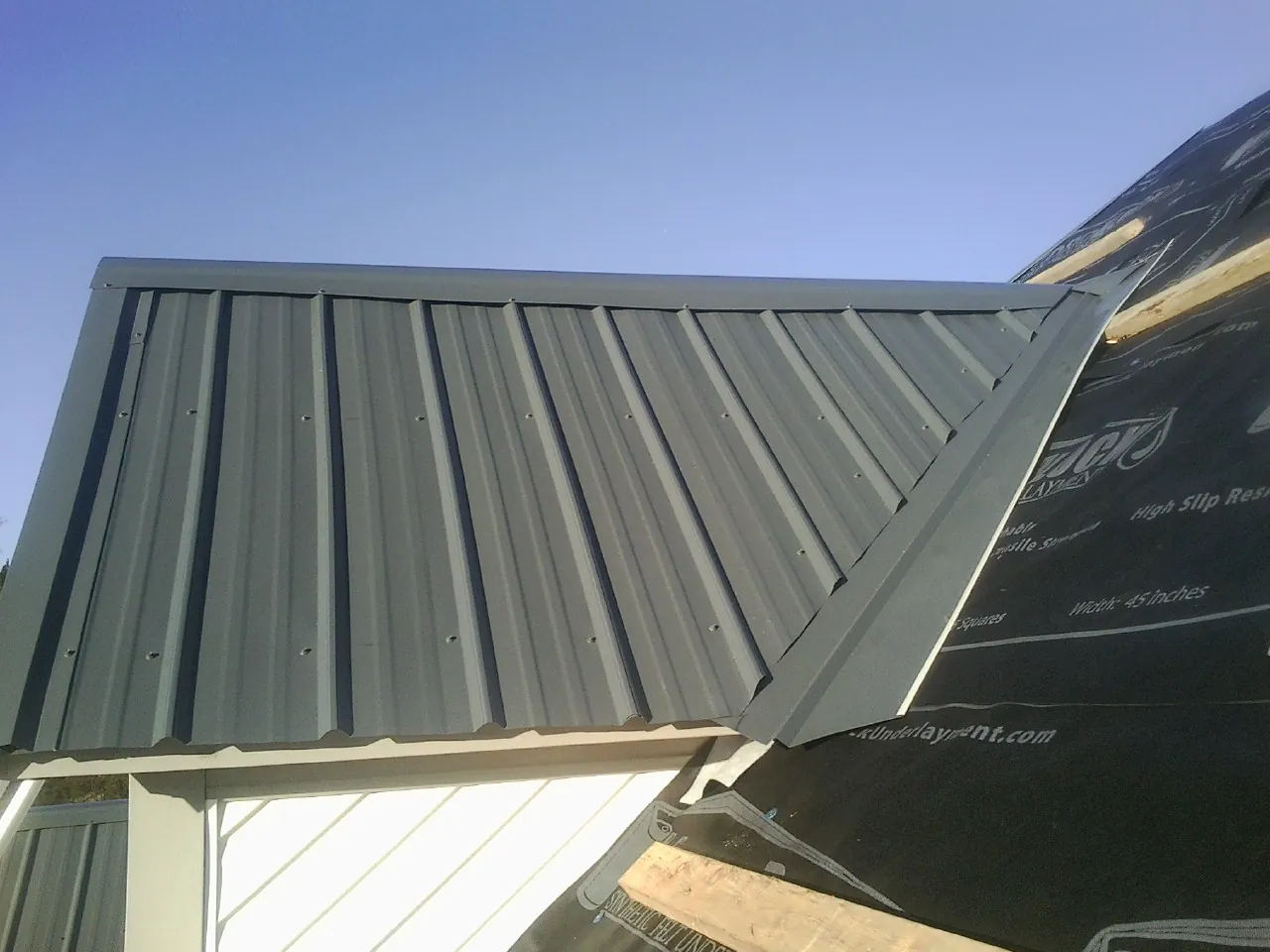 Gray metal roof panels going on over a garage gable in Goshen